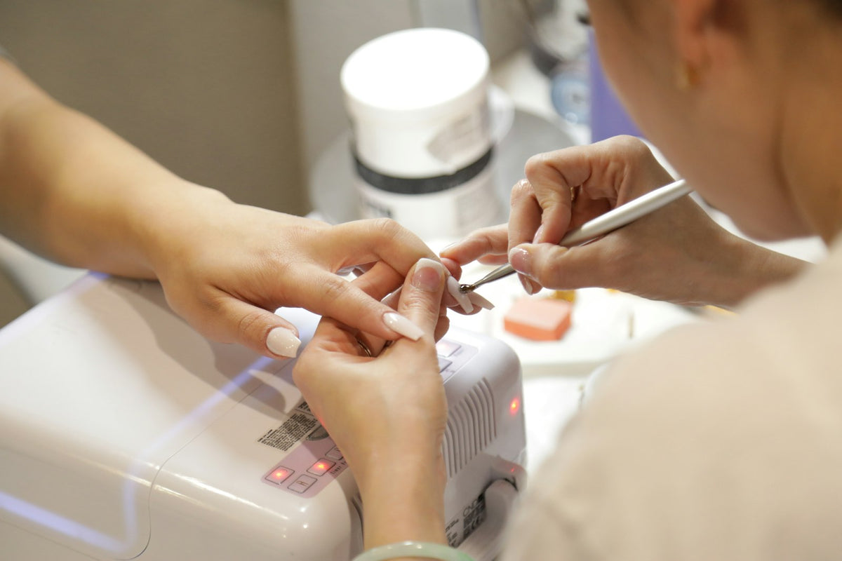 Esthéticienne ongulaire appliquant du vernis gel en salon professionnel